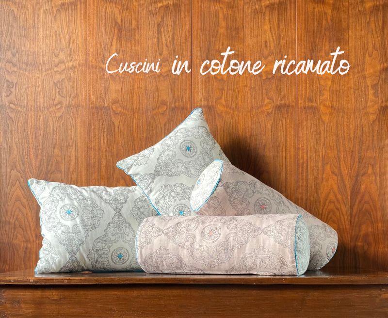 Set di cuscini d'arredo in cotone ricamato nelle eleganti tonalità del bianco, grigio, turchese e rosa pesca.