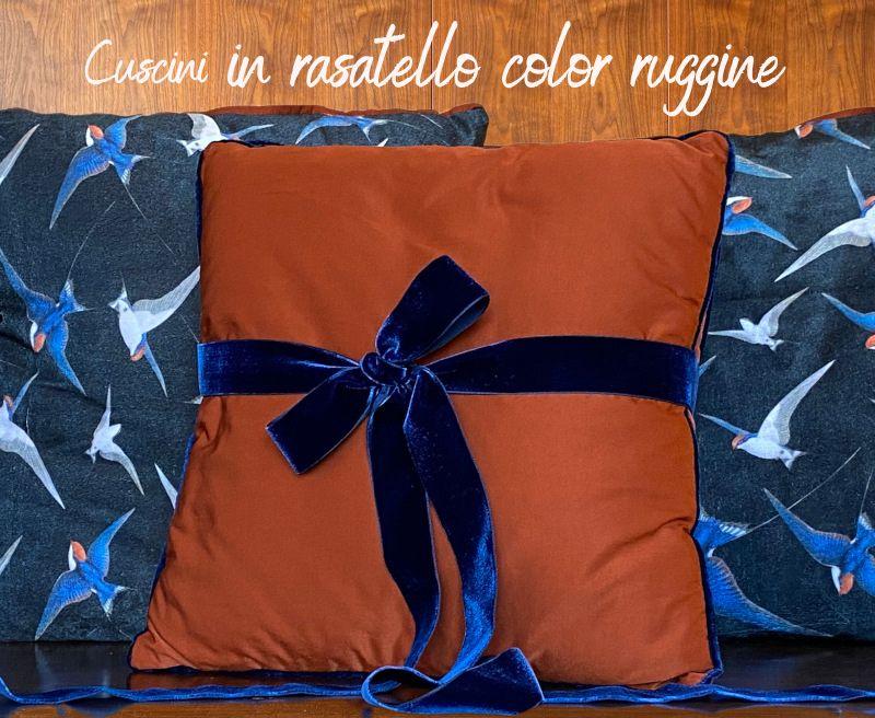 Cuscini in rasatello color ruggine con bordo in velluto blu, lavorazione artigianale.